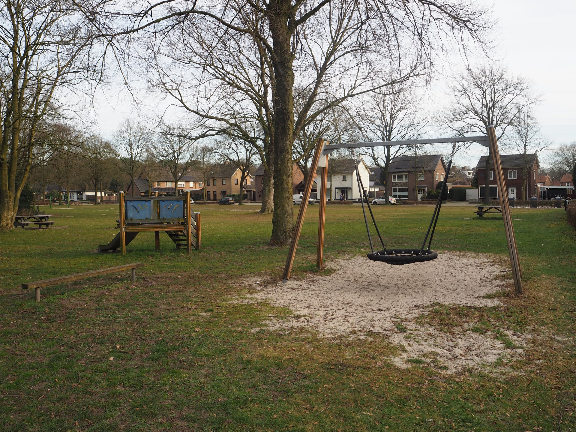 Vergroot afbeelding: aan de linkerkant een klimrek met glijbaan, rechts daarvan een schommel. Op de achtergrond staan woningen. 