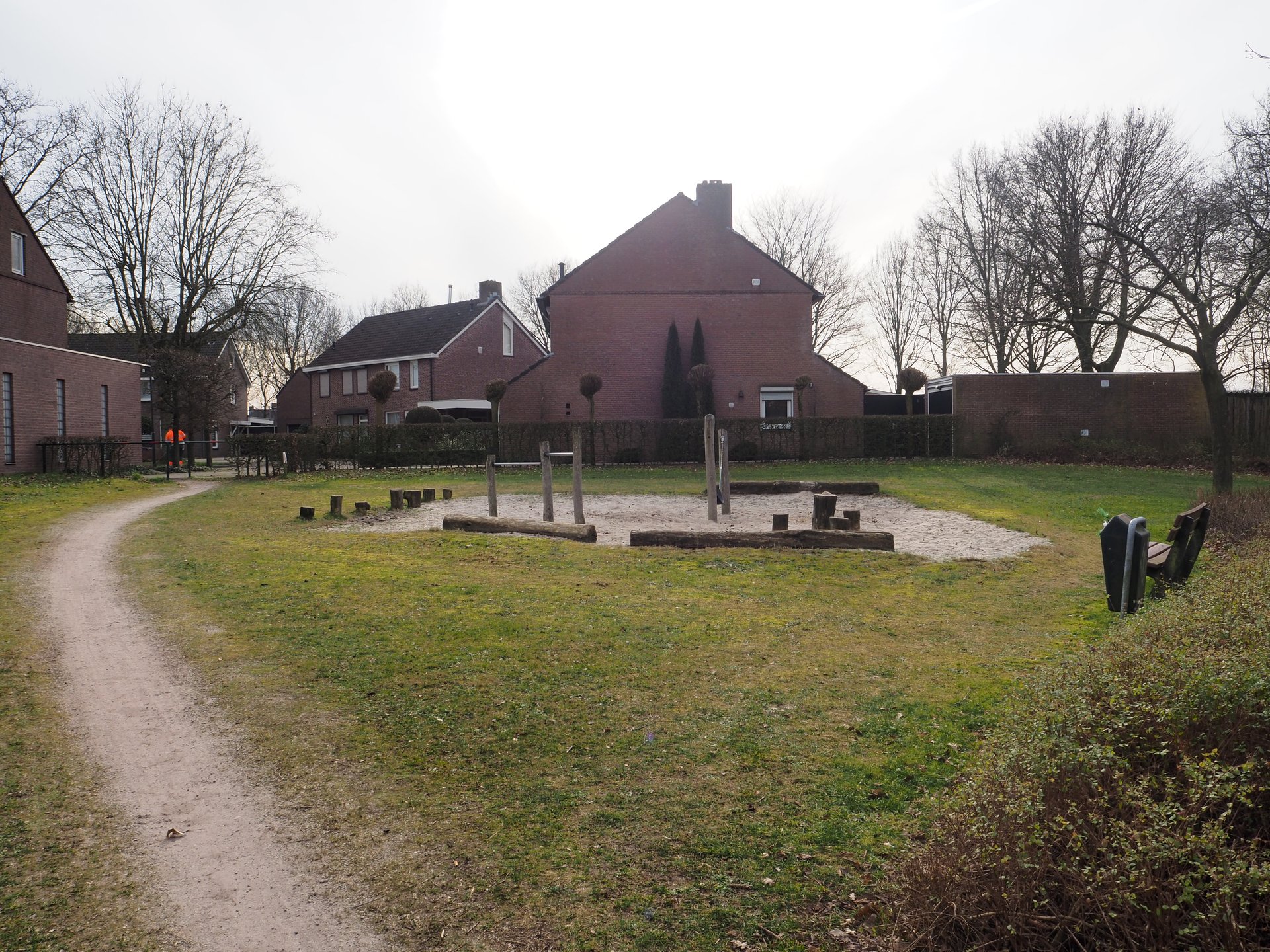 Vergroot afbeelding: aan de linkerkant een onverhard pad met rechts daarvan een zandbak met duikelrekken en boomstammen erin