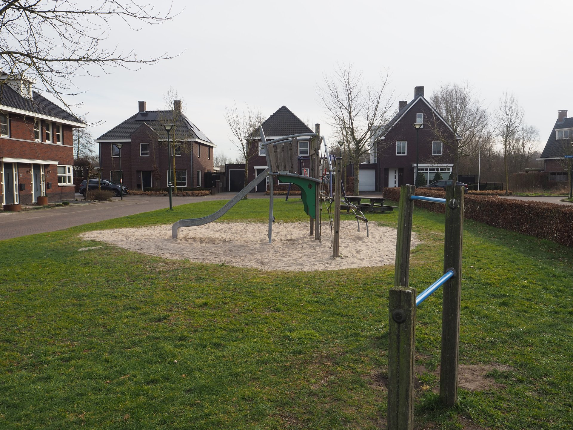 Vergroot afbeelding: een duikelrek en klimtoestel met glijbaan met op de achtergrond woningen