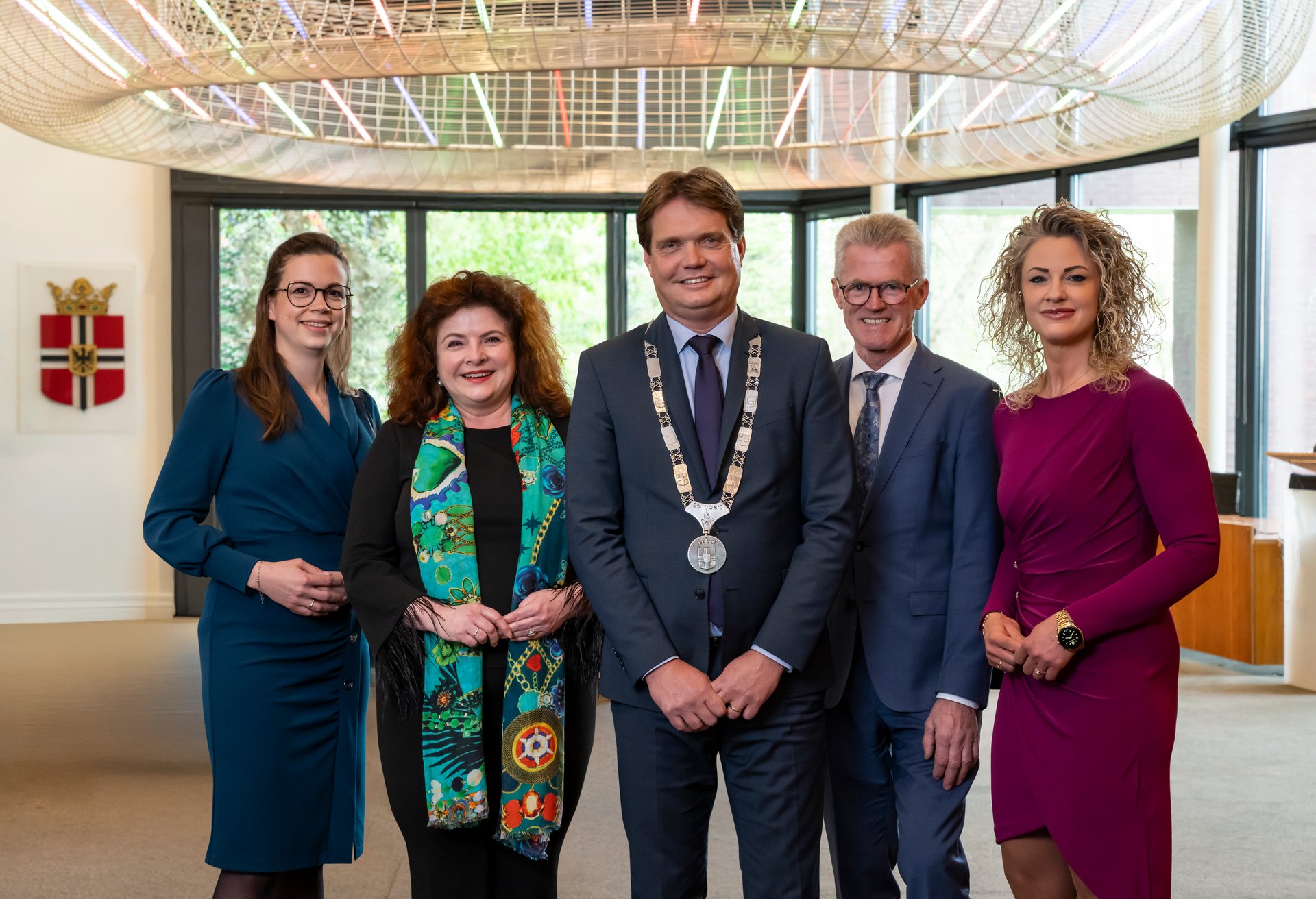 Vergroot afbeelding: van links naar rechts: wethouder Willeke van Zeeland, wethouder Wilmie Steeghs, burgemeester Michiel van Veen, wethouder Martien Bankers en wethouder Hanneke Coppens. Zij staan in de raadszaal in het gemeentehuis. 