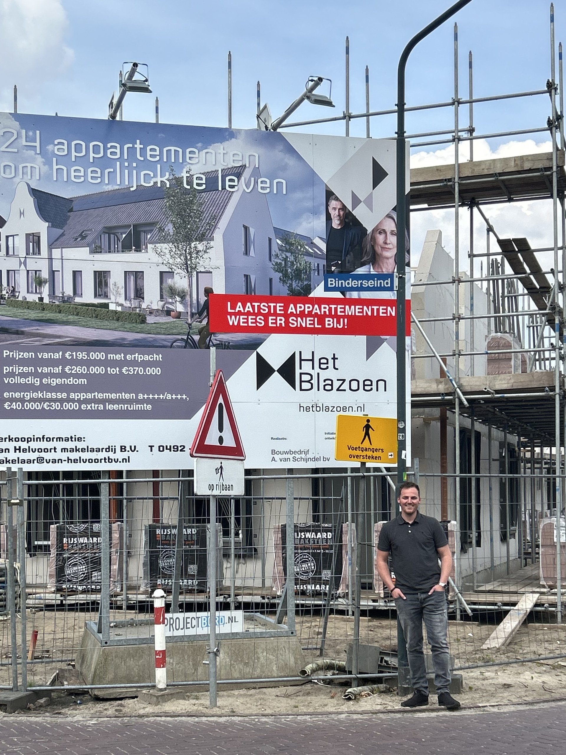 Vergroot afbeelding: Gemeenteraadslid Erik Schoone voor nieuwbouwproject Het Blazoen in Gemert. Op de achtergrond is het bord over het project te zien én zie je een stukje van de bouw.