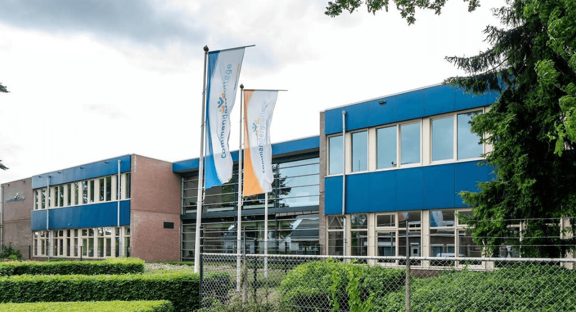 Vergroot afbeelding: het schoolgebouw met daarvoor de vlaggen van de school.