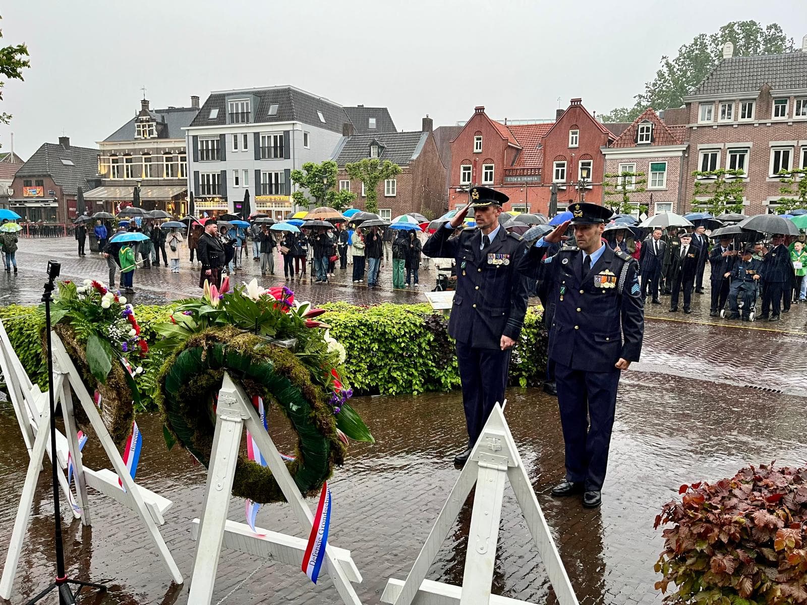 Vergroot afbeelding: 2 personen salueren bij de kransen op het Ridderplein.