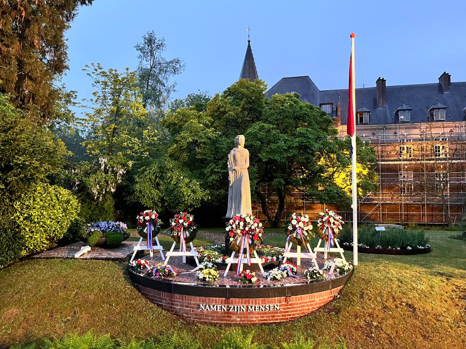 Vergroot afbeelding: een standbeeld met daarvoor de kransen. Op de achtergrond is het kasteel te zien.