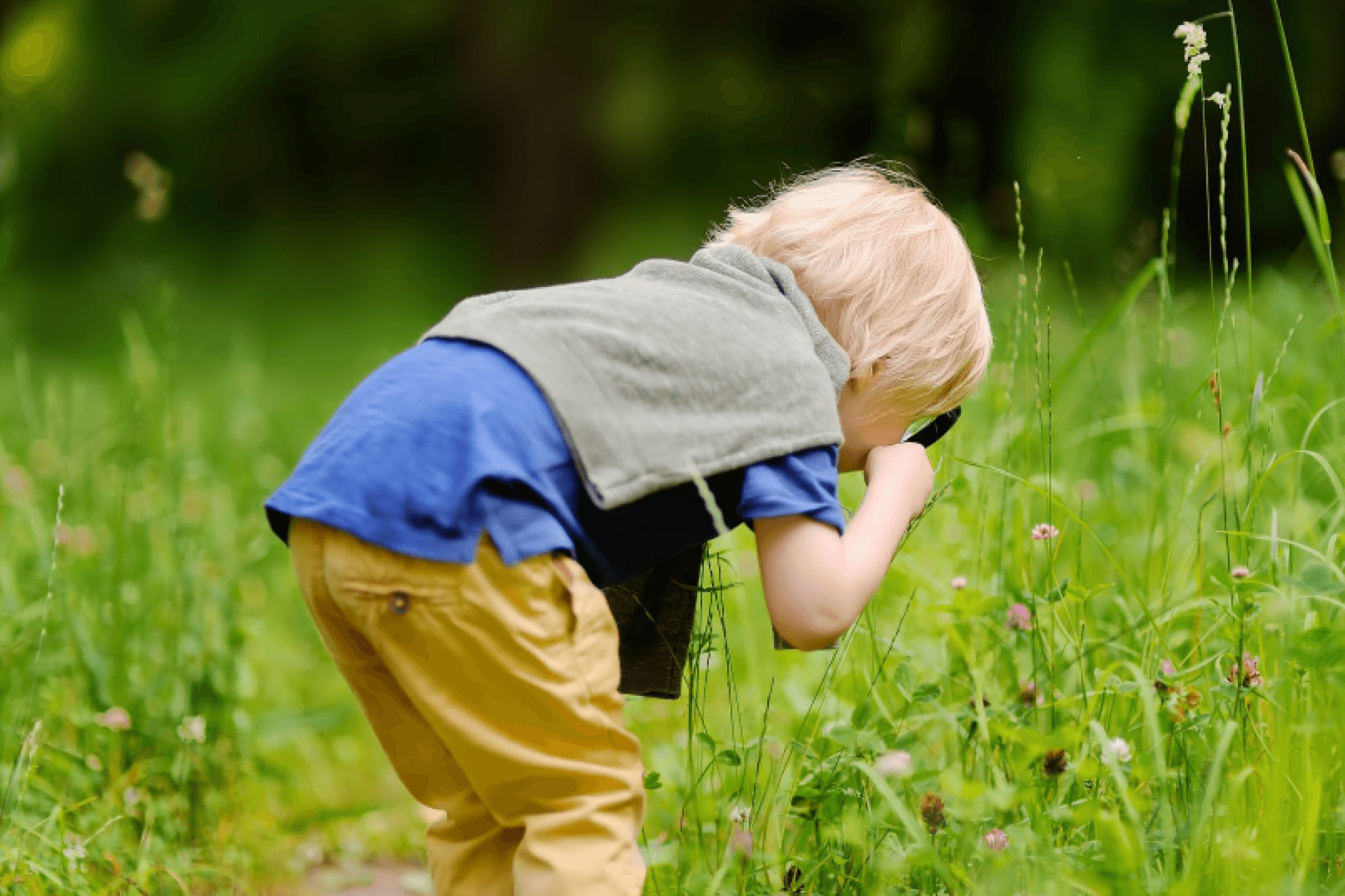 Kind kijkt door vergrootglas naar bloemen en grassen